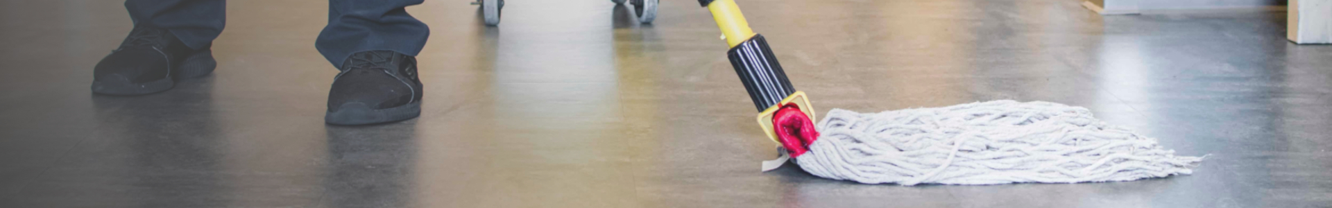 Mopp rengjør gulv ved siden av person med svarte sko.
