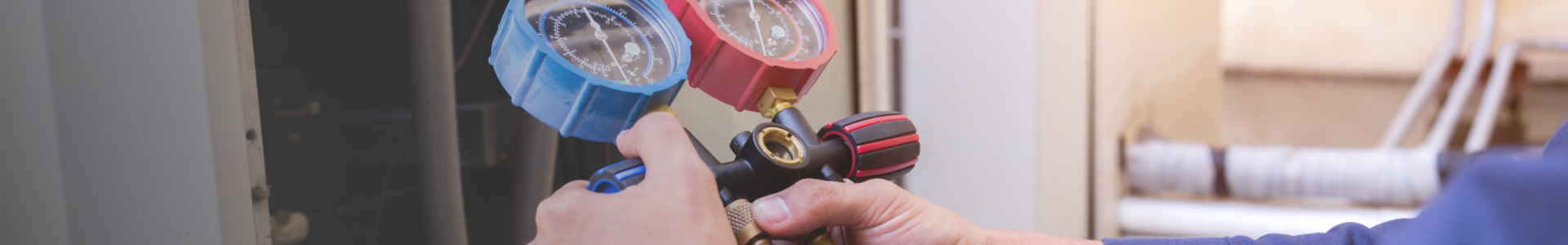 Hender justerer manometer med blå og rød trykkmåler på utstyr.