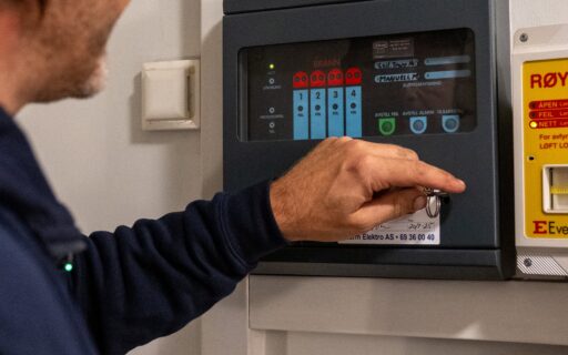 Vaktmester kontrollerer brannalarmpanelet i et bygg